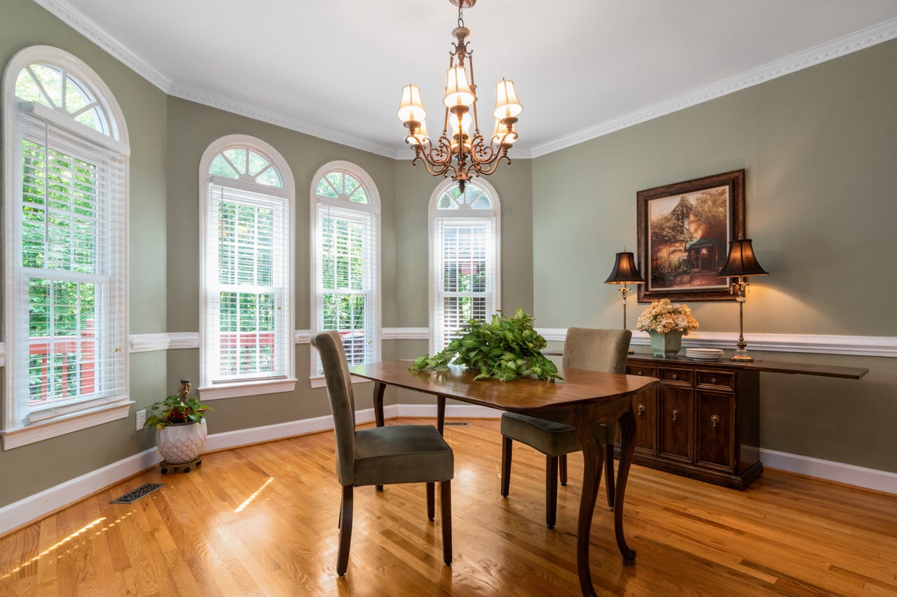 Beautifully designed dining room featuring arched windows, hardwood floor, and elegant chandelier.